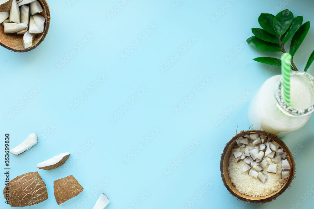 Coconut cut into pieces, coconut shavings, green leaves, shea butter on a blue background. A place for text. Coconut cut into pieces, coconut shavings, green leaves, shea butter on a blue background. A place for text.