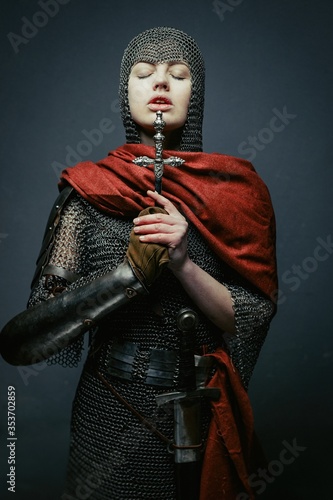 Photo Gorgeous young woman in knight armour and steel chainmaille holding dagger on dark background