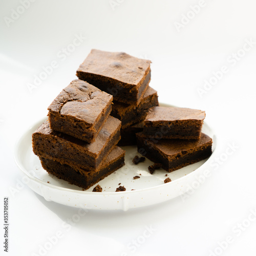 Chocolate brownie sliced into square slices on a white plate.
