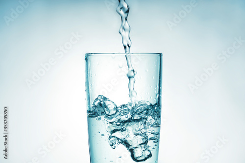 Close up of pouring purified drinking water from a bottle with bubbles and splashes on a white background