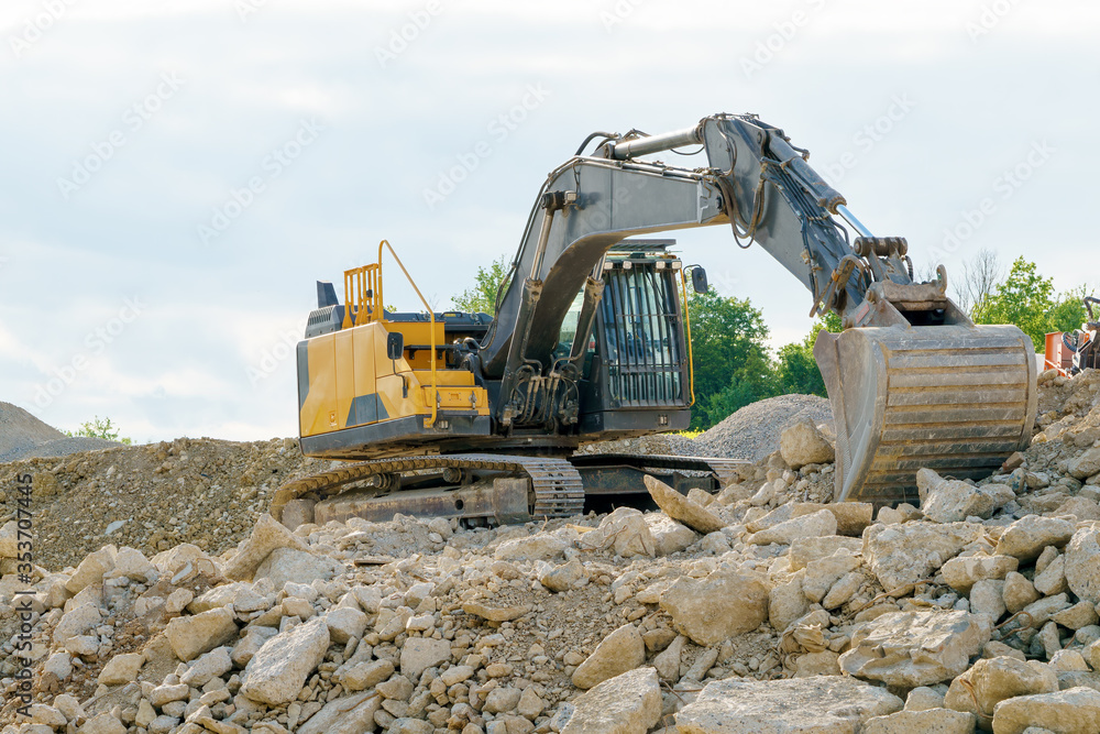 Obraz premium A yellow excavator on a pile of gravel
