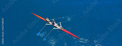 Aerial drone top ultra wide panoramic view of sport canoe rowing synchronous female athletes competing in deep blue sea
