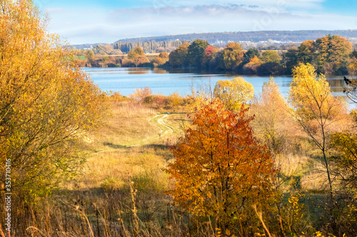 Autumn landscape with colorful trees by the river in sunny weather