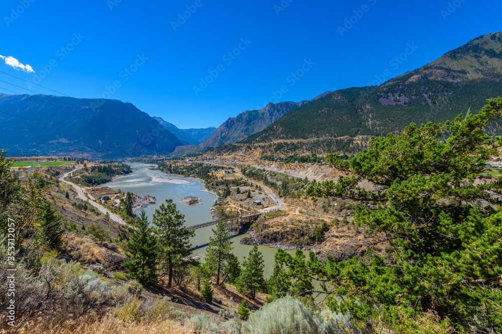 View of beautiful landscape in the Rocky Mountains with fresh blue and green mountain river water and mountain tops in the background on a sunny day with blue sky in springtime.