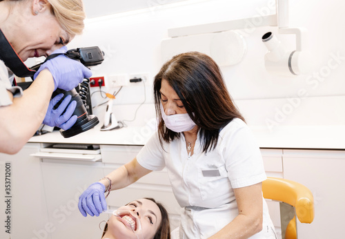 Dentist photographing a young patient s mouth while the nurse holds her mouth open.