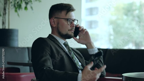 Handsome businessman in eyeglasses talking on the mobile phone in office. 4k uhd photo