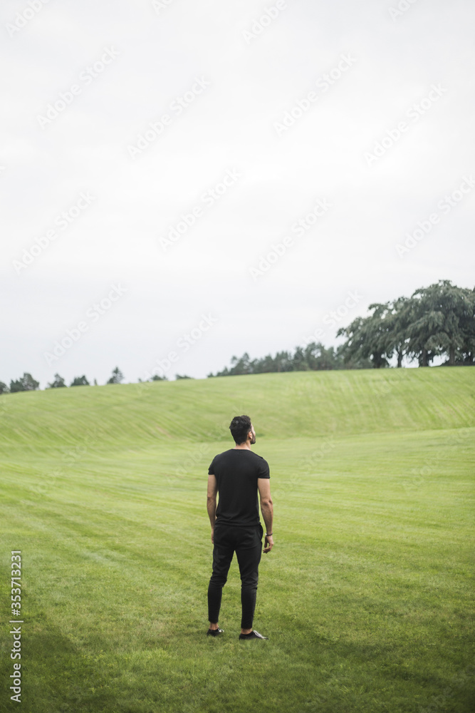 Rear view of young man standing on agricultural field against sky Rear view of young man standing on agricultural field against sky