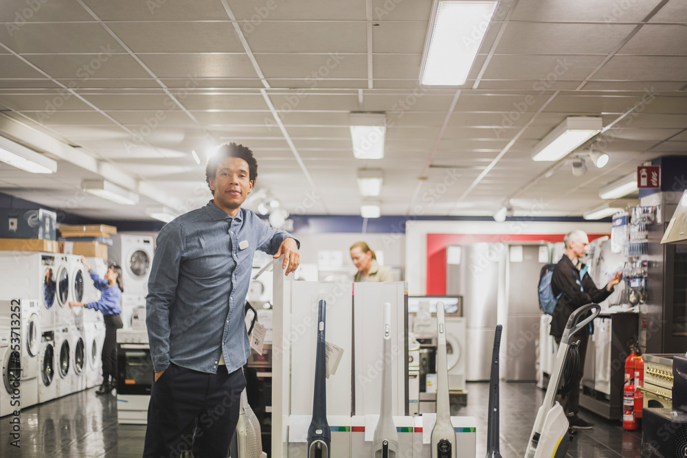 Portrait of male owner with hand in pocket standing in electronics store Portrait of male owner with hand in pocket standing in electronics store
