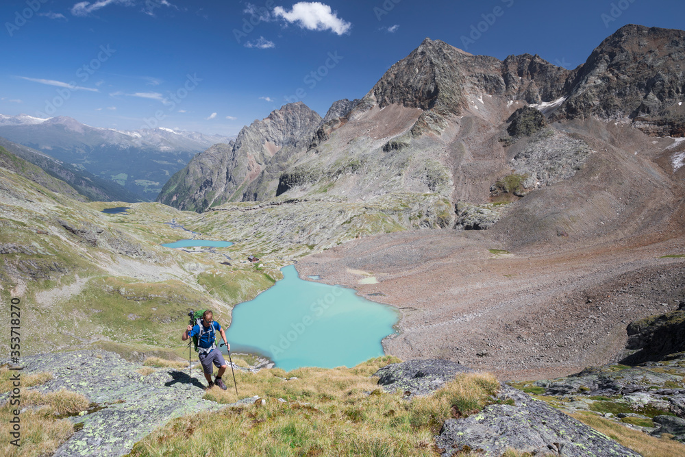 Hiking person at turquoise lake Gradensee at Nossberger Hut, mountains and valley, in Gradental in national park Hohe Tauern, Austria.