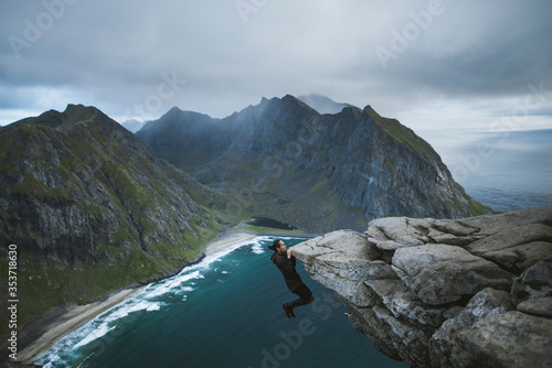 Man hanging off cliff at Ryten mountain in Lofoten Islands photo