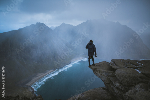 Man holding camera on cliff at Ryten mountain in Lofoten Islands, Norway photo