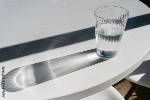 Glass of water on table making shadows photo