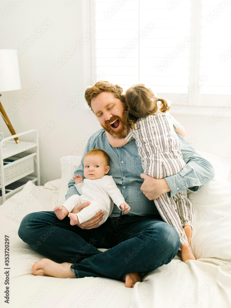 Father sitting on bed with children (2-3 months, 2-3) Father sitting on bed with children (2-3 months, 2-3)
