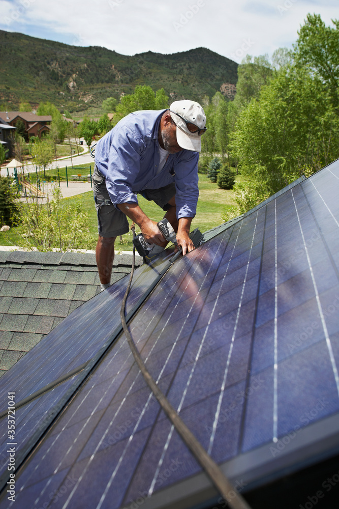 Construction worker installing solar panel on roof Construction worker installing solar panel on roof