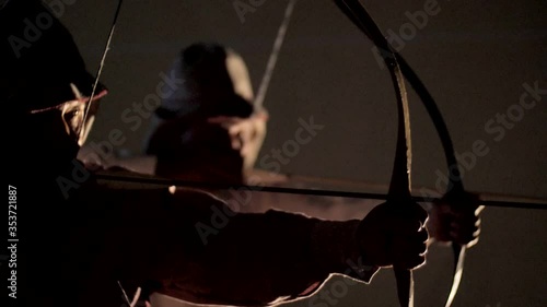 Two men are shooting arrows in a dark room. Archery. Historical Archery