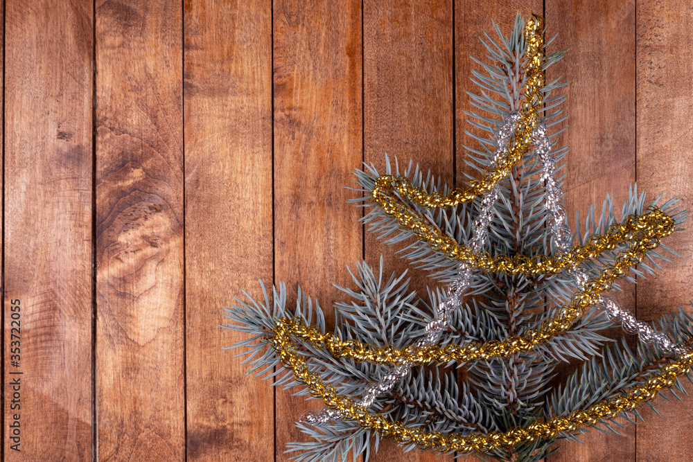 a sprig of spruce in the form of a small tree decorated with golden and silver rain lies on a brown wooden surface a sprig of spruce in the form of a small tree decorated with golden and silver rain lies on a brown wooden surface