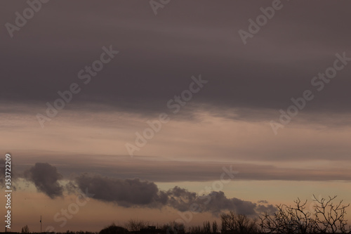 Fototapeta Naklejka Na Ścianę i Meble -  Unusual rain clouds of different colors at sunset over the trees