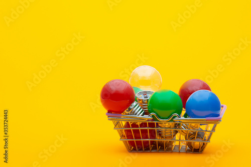 multi-colored light bulbs in a metal basket on a yellow background