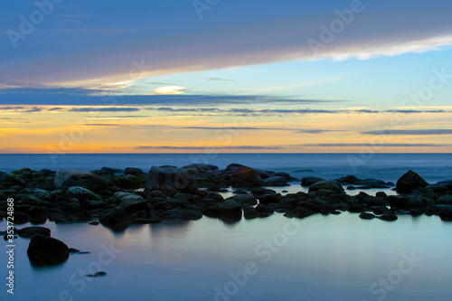 Sunset Over Ocean With Stones In Foreground