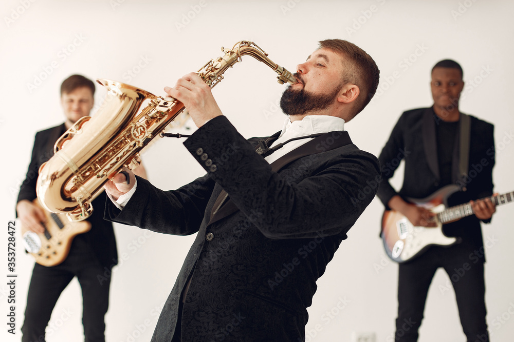 Fototapeta premium Music band in a studio. Guy in a black suit. Musician with saxophone.