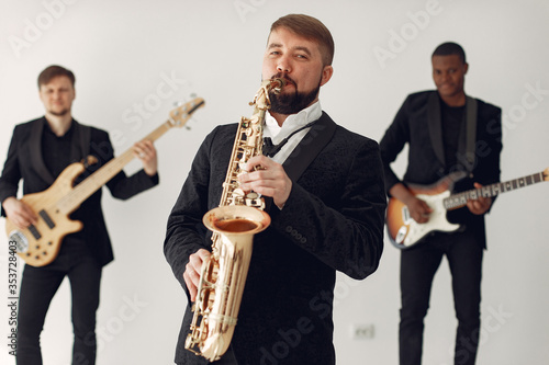 Music band in a studio. Guy in a black suit. Musician with saxophone.