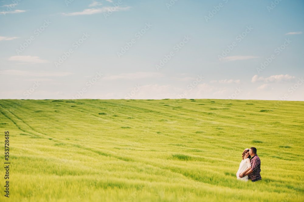 waiting baby. Parenthood. Pregnant young woman and her husband are happy to hold hands, going in the outdoor in the field of green grass background. selective focus. waiting baby. Parenthood. Pregnant young woman and her husband are happy to hold hands, going in the outdoor in the field of green grass background. selective focus.