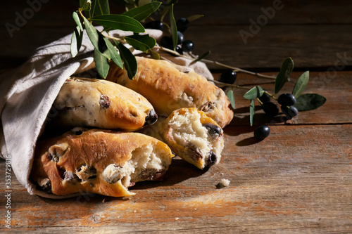 Traditional italian puccia breads with black olives in a cotton bag, made in Salento, Puglia on a wooden background photo