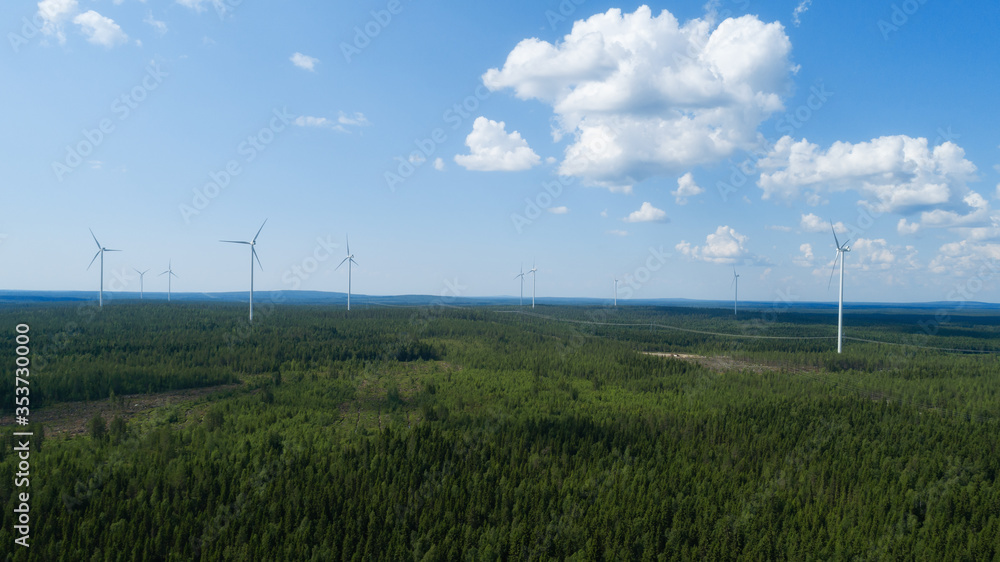 Wind turbine near green forest, beautiful aerial landscape with blue sky. Alternative energy concept. Wind turbine near green forest, beautiful aerial landscape with blue sky. Alternative energy concept.