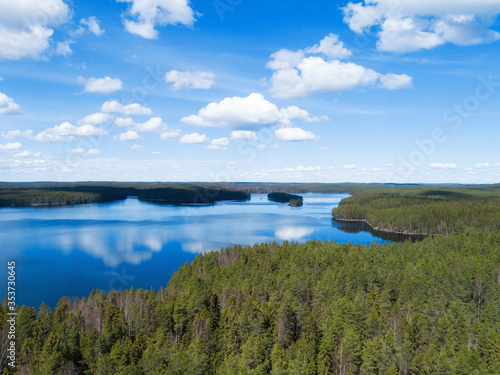 Sunny landscape in Finland with beautiful lake, forest and blue sky with some clounds. Amazing scandinavian nature, travel and hiking tourism destination.