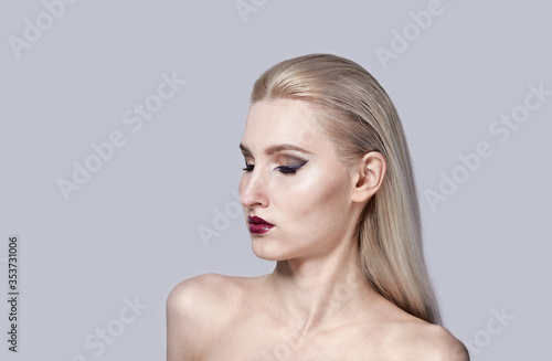 Bright make-up in a woman with bare shoulders. Stylish haircut.