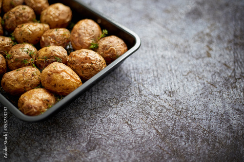 Homemade roasted whole potatoes in jackets. With butter, rosemary and thyme. Served in metallic dish