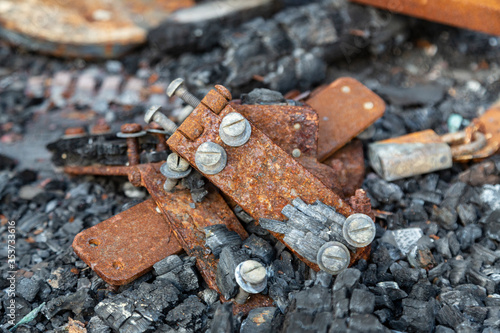 A close-up view of a pile of rusted hinges and fire damaged,chard rubble 