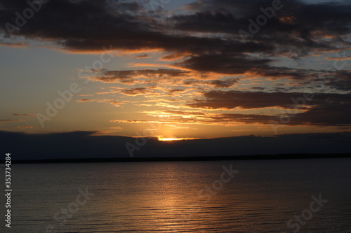 Bronze dawn over the lake.Glimpses of the rising Golden sun illuminate colorful chocolate clouds and calm ripples of water.Beautiful landscape of coffee shades
