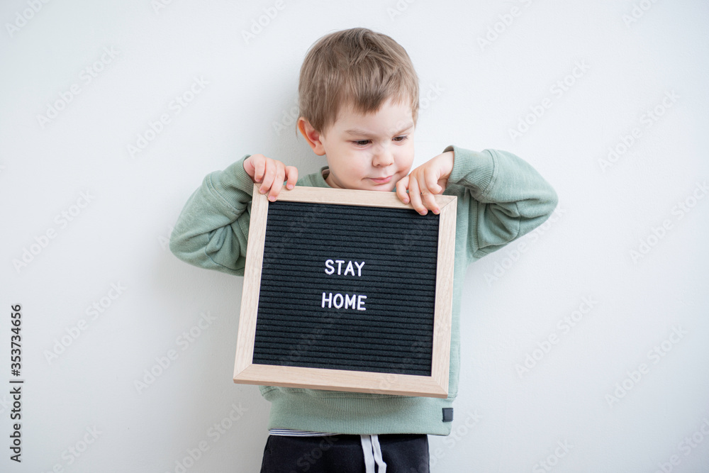 Toddler boy holding a felt letter-boad written Stay home. Stay home because of quarantine and self isolation. Social distancing. Toddler boy holding a felt letter-boad written Stay home. Stay home because of quarantine and self isolation. Social distancing.