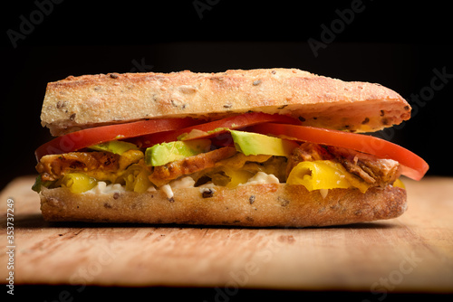 Meat sandwich with avocado, tomato, mayo, chilli in a baguette
