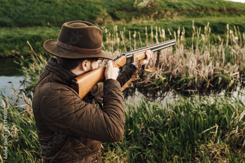 Vintage hunter walks. Rifle Hunter Silhouetted in Beautiful Sunset or Sunrise. Hunter aiming rifle in swamp and field