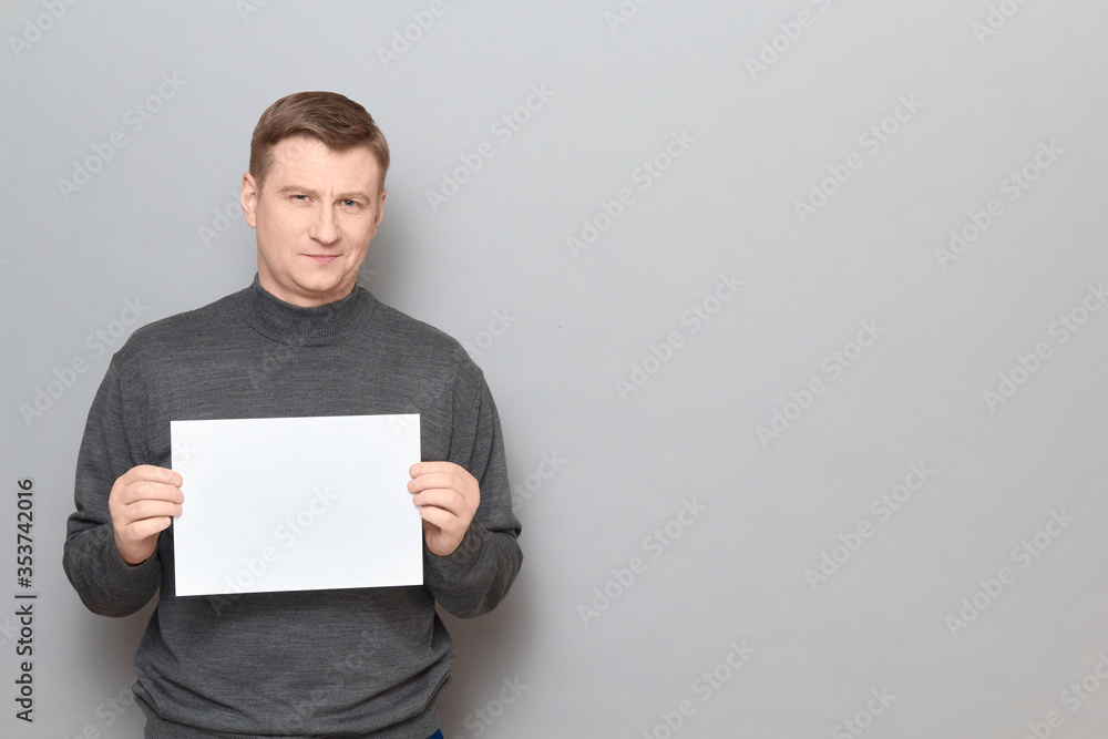 Portrait of happy man holding white blank paper sheet in hands Portrait of happy man holding white blank paper sheet in hands