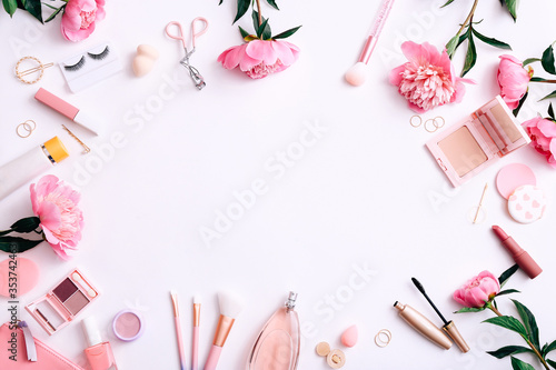 Beauty background with facial cosmetic products and peonies on white desktop background. Top view, flat lay.