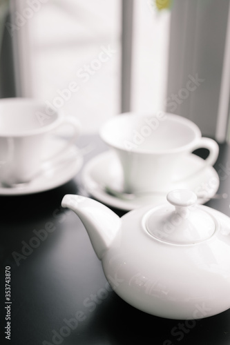 a white teapot with a white Cup on a black table