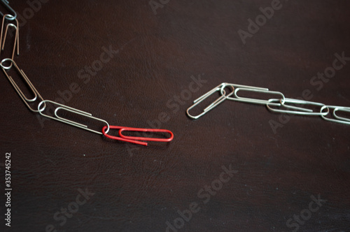 Broken chain built with paper clips with a red one