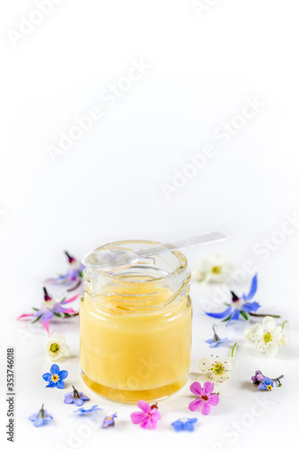 Raw organic royal jelly in a small bottle with litte spoon on small bottle on white background 