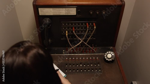 Stressed out woman operator switching tangled telephone switchboard cables