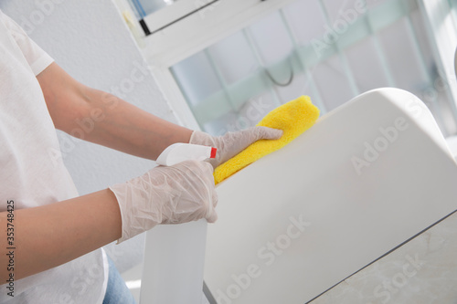  Women work at home using alcohol spray or antiseptic to clean house to prevent spreading of coronavirus during crisis of covid-19. housework, work from home and social distancing concept.