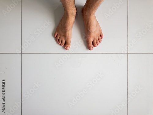 Man's feet on white floor ceramic tiles
