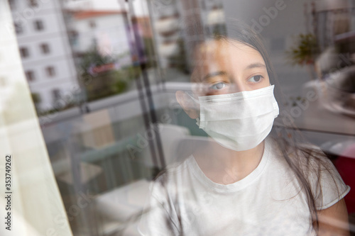 Quarantine coronavirus pandemic prevention.Child in protective medical masks stay at home and looks out the window. Prevention of epidemic.Outbreak.