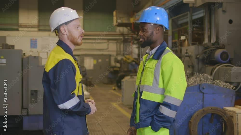 Diverse factory technicians communicating inside industrial plant Diverse factory technicians communicating inside industrial plant