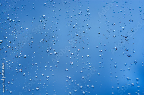 gotas de lluvia sobre vidrio en fondo azul