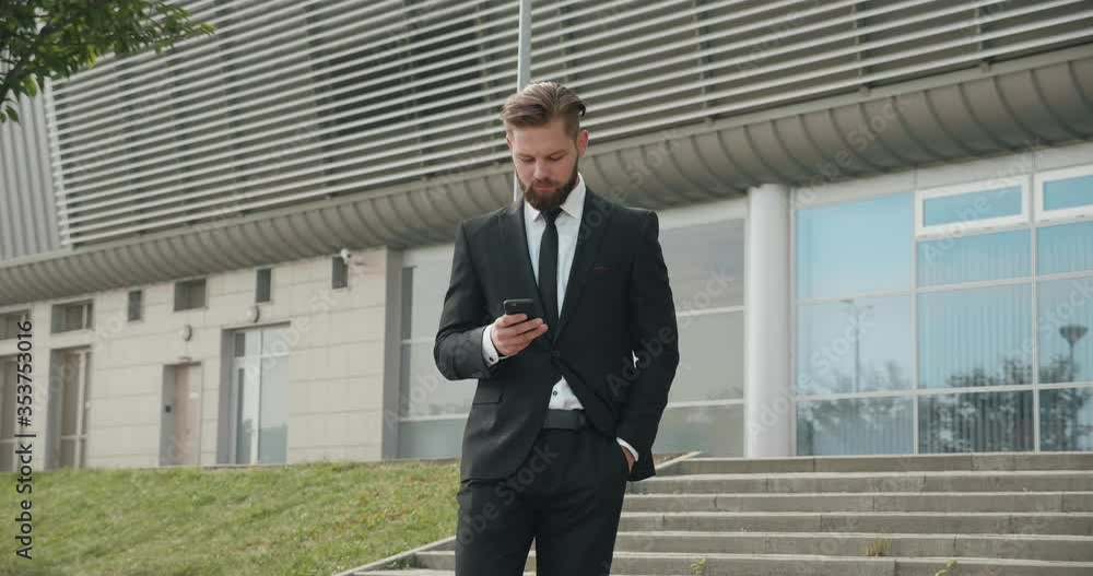 Attractive Businessman walking one foggy morning by the Airport Building with Mobile Phone. Working outdoor Office building, Using different apps. Looking serious and Confident. Having formal Suit. Attractive Businessman walking one foggy morning by the Airport Building with Mobile Phone. Working outdoor Office building, Using different apps. Looking serious and Confident. Having formal Suit.