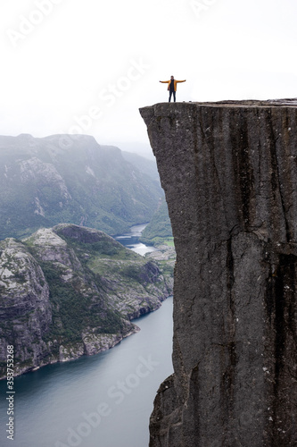 Trip to Norway. Man stays alone on the Preikestolen mountain cliff (Preacher's Pulpit or Pulpit Rock) with Lysefjord on background in foggy summer day
