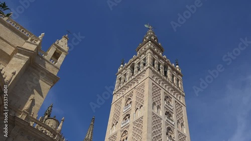 4K. Ultra HD. View of La Giralda Tower with a clear blue sky in the background. Bell tower of the cathedral. The largest cathedral in the world located in Seville, Spain. 